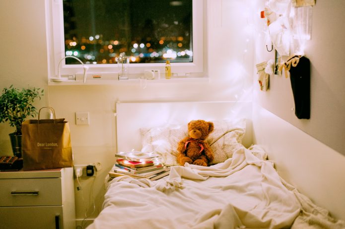 A decorated student halls room with fairy lights and a plant.