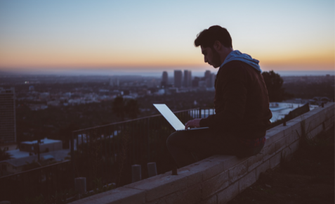 man sat on a wall working looking over a city