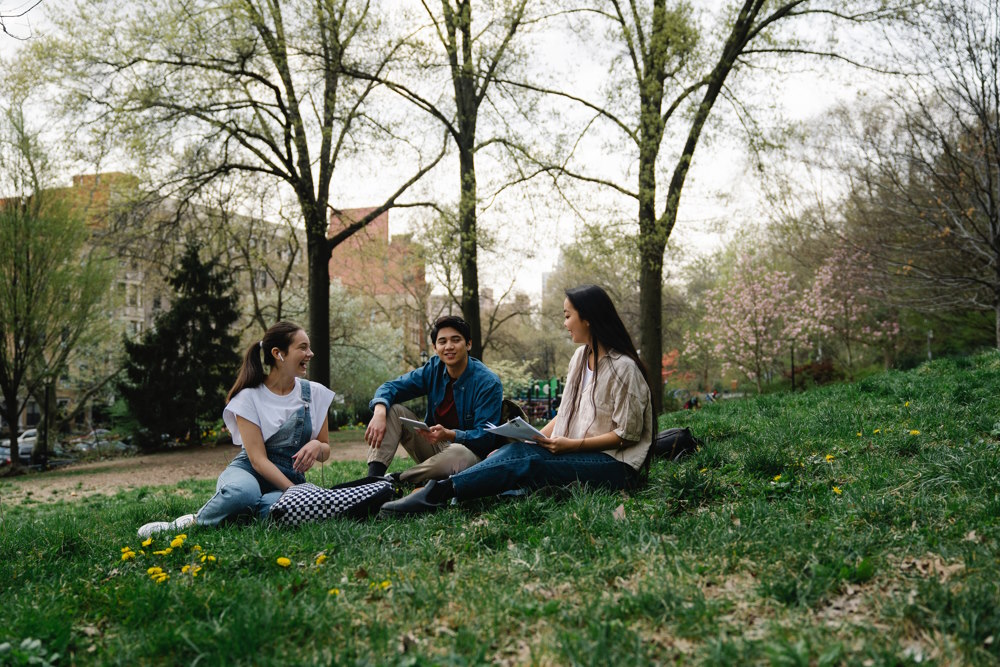 A group of friends sitting on grass and chatting.