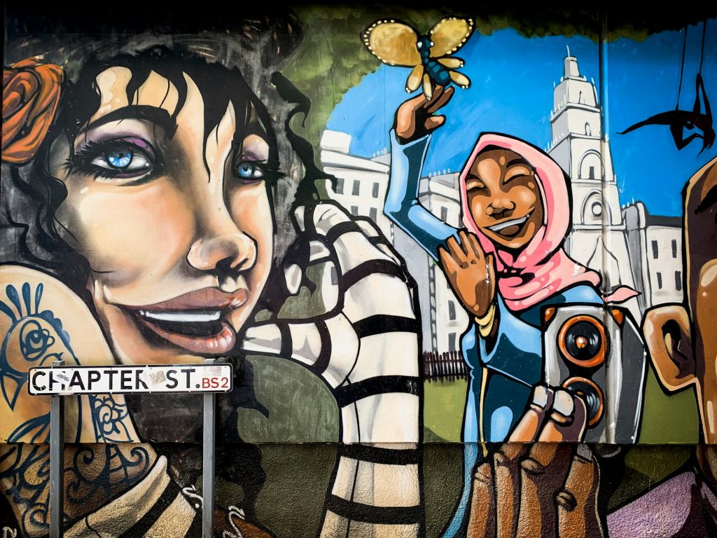 Street art mural on Chapter Street in St Pauls, Bristol, with the street sign in front