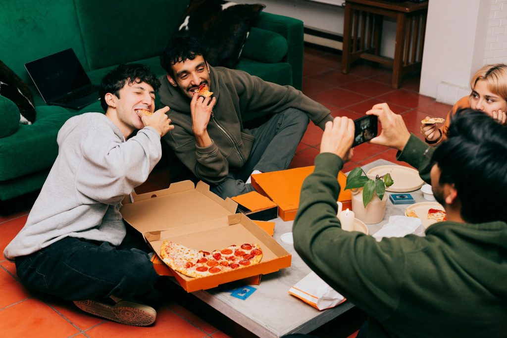 A group of friends sharing pizza around a table at home