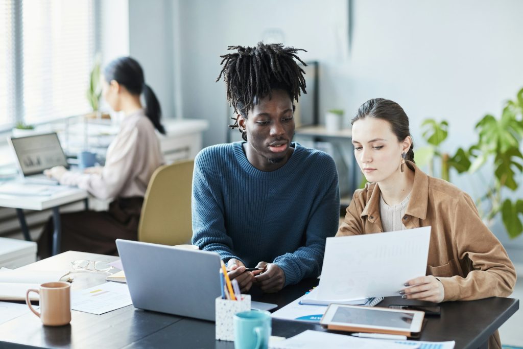 Two young people looking at a laptop together at a desk”